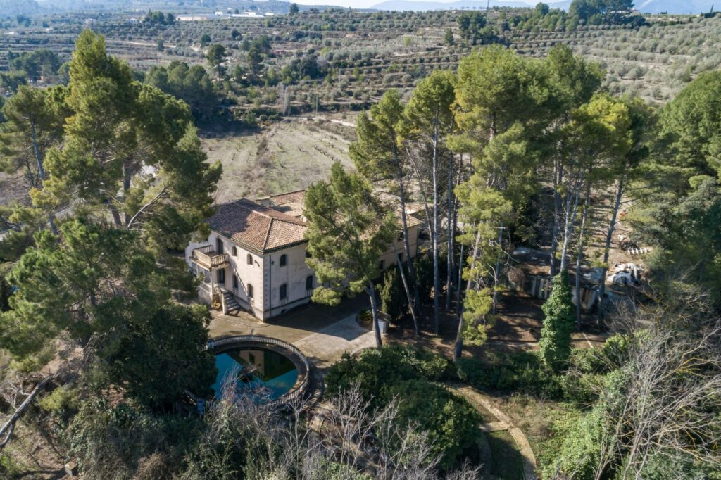 Aerial picture of the residential building also showing olive trees and the pond.